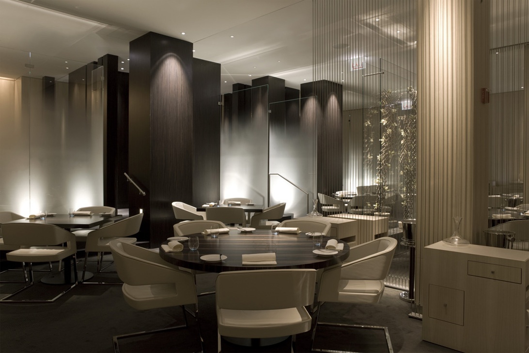 En elegant hotellrestaurang med sofistikerad modern design, mörka träpelare och stämningsfull belysning.